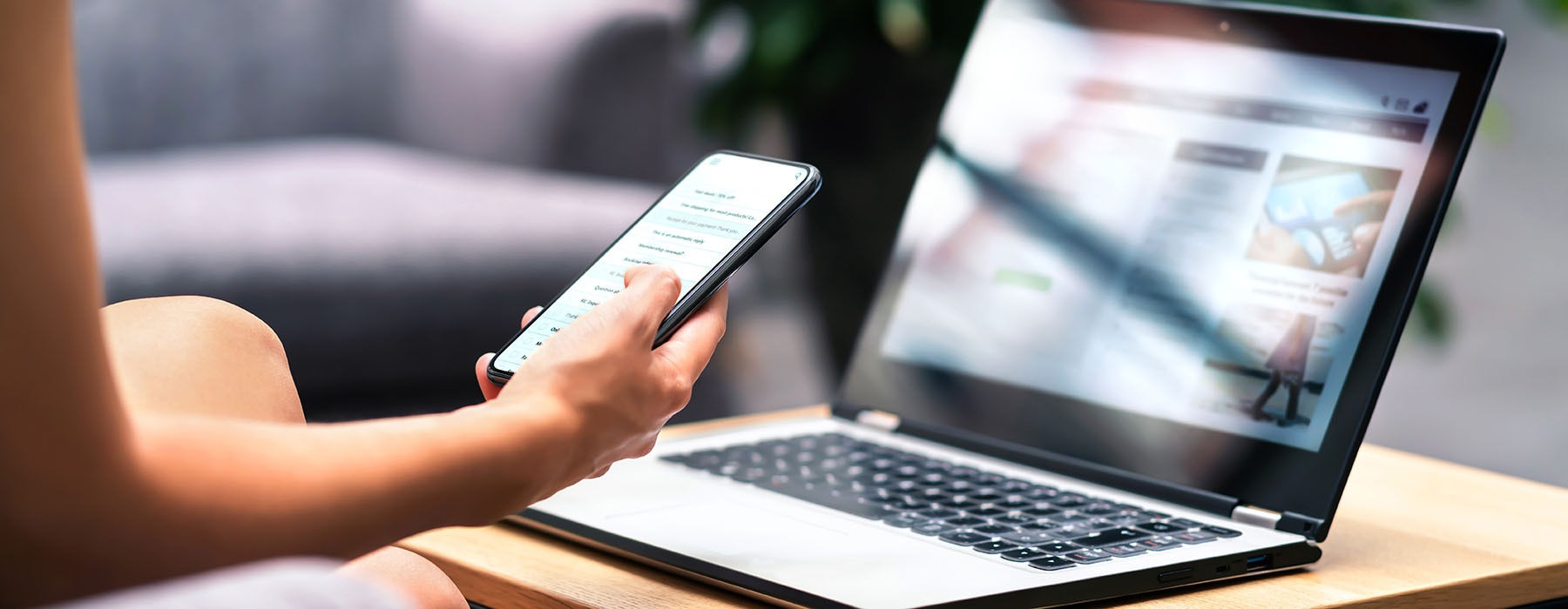 woman holding a phone in front of a laptop