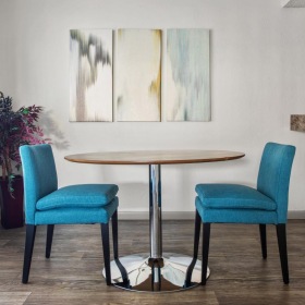 All the comforts of luxury living a room with a table chairs and a painting on the wall